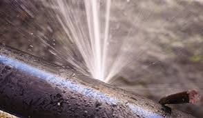 Close-up of a burst pipe spraying water under pressure