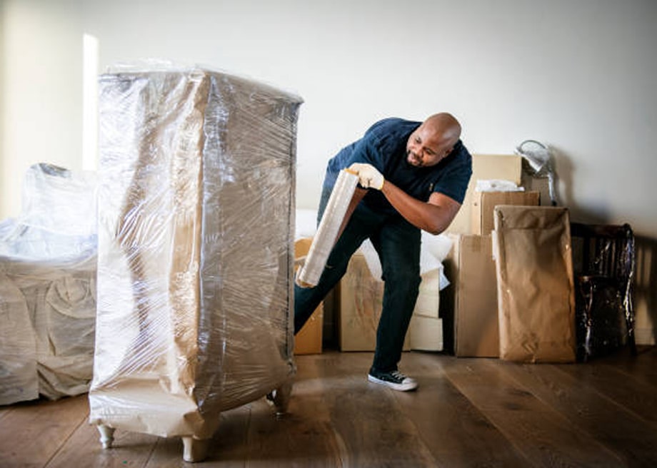 Technician wrapping and packing out furniture for contents restoration after water damage