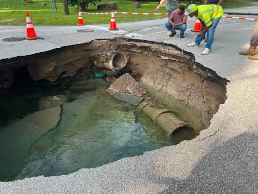 A large sinkhole has opened in a residential street, exposing broken water and drain pipes